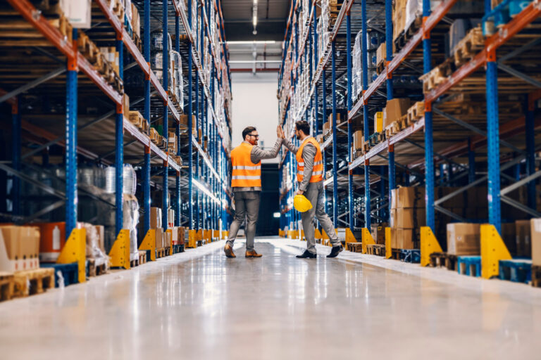 Titelbild für Smart Logistics Quick Check: zwei Männer im Lager von hinten, die sich Einklatschen und ein High Five geben